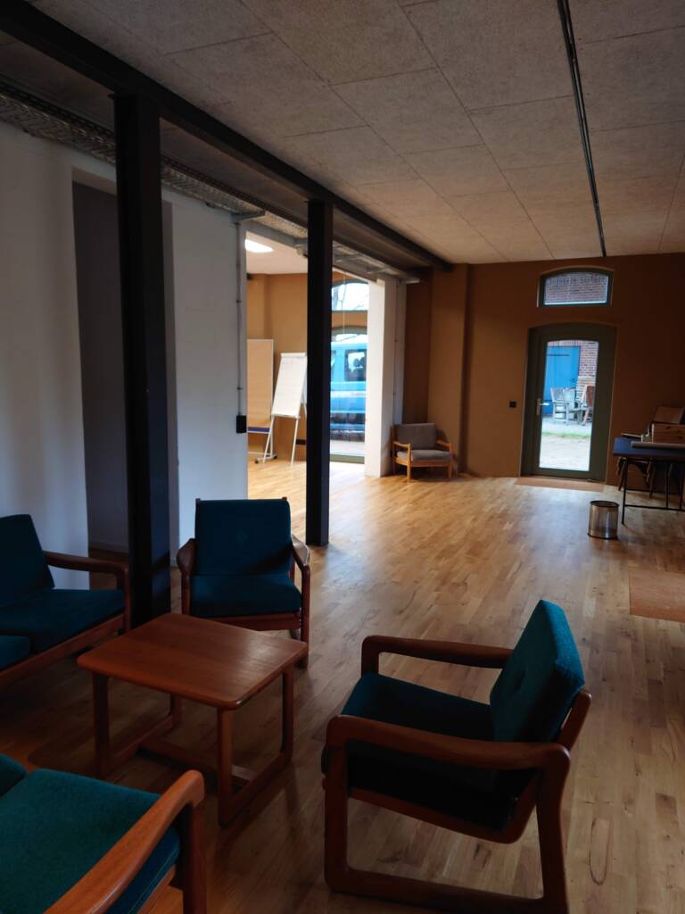 Innenansicht eines modernisierten Altbaus mit Holzfußboden, Sitzmöbeln und Stahlstützen.