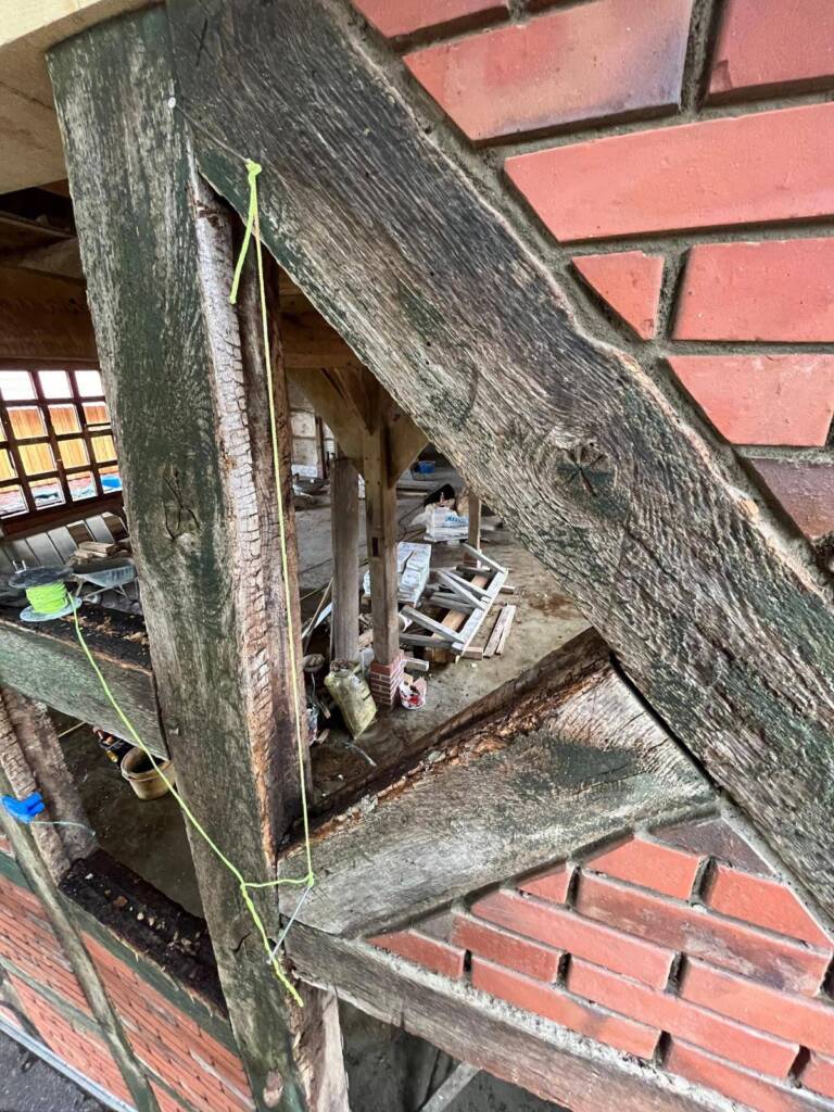 Detailaufnahme eines historischen Fachwerkhauses mit Sicht auf verwitterte Holzbalken und Ziegelmauerwerk.