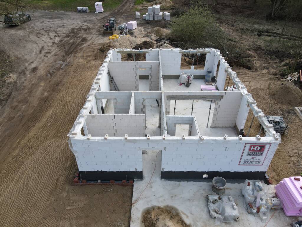 Luftaufnahme eines Neubaus mit bereits angelegten Innenwänden aus weißem Mauerwerk.