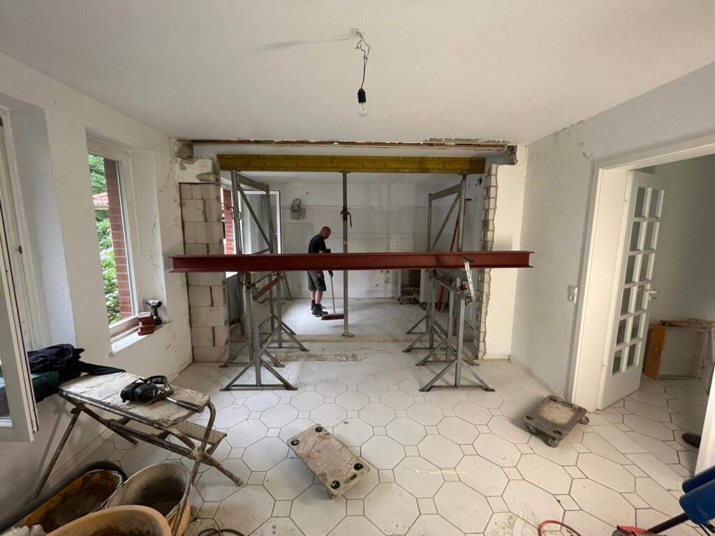 Umbau eines Wohnraums mit gestütztem Träger und vorbereiteter Wandöffnung.